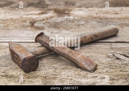 old hammer and rusty chisel on a wooden unpainted workbench Stock Photo