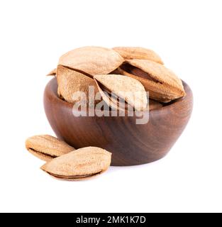 Mountain almonds in wooden bowl, isolated on white background. Uzbek wild almonds Stock Photo