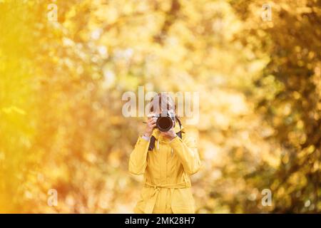 Lady Photographed Nature. Tourist Woman Walking And Taking Photos In Forest. Young Pretty Caucasian Happy Smiling Girl Woman On Road In Autumn Forest Stock Photo