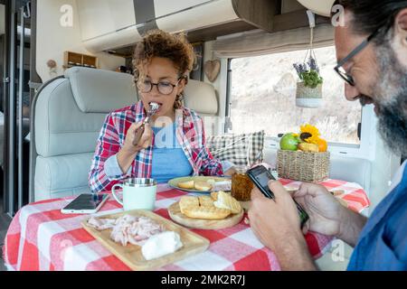 Man and woman eating lunch together using phone without talk each other. Couple of modern traveler using connection roaming device mobile cell at the Stock Photo