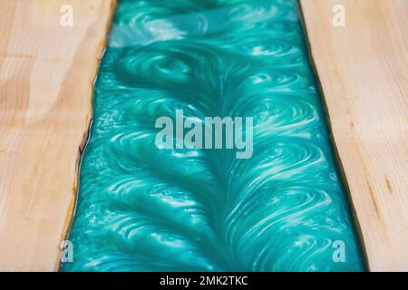 liquid turquoise epoxy on the kitchen table in the workshop Stock Photo