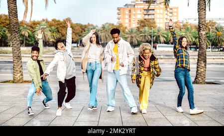 Multicultural friends walking at Barcelona boardwalk on funny mood - Genz guys and girls acting crazy move by urban street on party behaviour Stock Photo