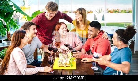 Young friends having fun together tasting wine at rooftop by private house lounge - Happy people eating finger food at restaurant - Dinning life style Stock Photo