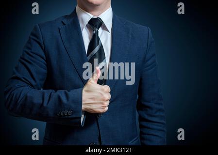 Businessman in suit showing Good sign with his thumb up on blue background Stock Photo