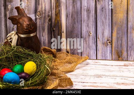 Easter bunny with a nest with colorful Easter eggs in the stable Stock Photo