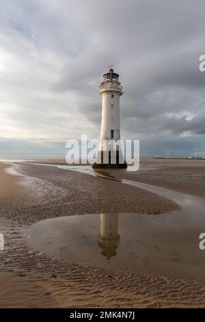 New Brighton, UK: Perch Rock Lighthouse reflected in water pools at low tide. An iconic landmark on the Wirral peninsula. Stock Photo