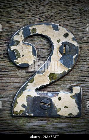 painted brass house number with flaking paint Stock Photo
