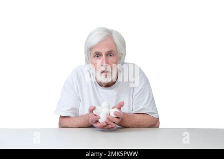 Horizontal shot of an old man sitting at a table with his hands full of eggs looking very surprised or frightened.  Isolated on white.  Lots of copy s Stock Photo