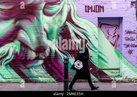 A Young Woman Walks Past Graffiti In The Brick Lane Area, East London, London, UK. Stock Photo