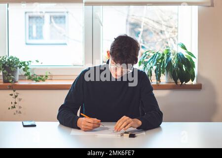 Brown-haired young architect creates new product designs for a new futuristic world. Working with your own creativity. Compass, pencil, ruler and pape Stock Photo