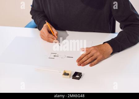 Brown-haired young architect creates new product designs for a new futuristic world. Working with your own creativity. Compass, pencil, ruler and pape Stock Photo