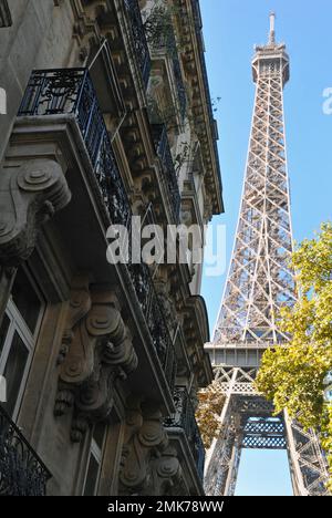 The Eiffel Tower rises behind ornate residential buildings at the end of Rue de l'Université in Paris' 7th arrondissement. Stock Photo