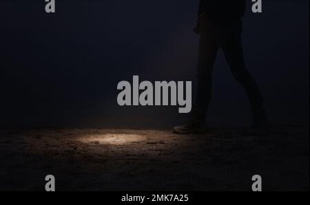 Man with flashlight walking near river at night, closeup Stock Photo