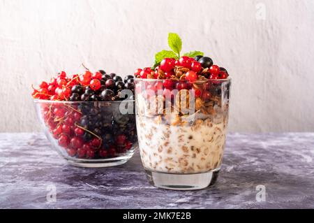 Breakfast with granola and various currants. Granola and various currants. Red and black currant. Front view. Stock Photo