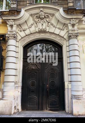 Large carved double doors are surrounded with columns and cherub head over the door entry way made out of cement or carved stone. Stock Photo