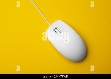Wired computer mouse on yellow background, top view Stock Photo