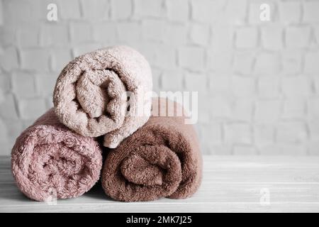 Fresh rolled bath towels on white wooden table. Space for text Stock Photo