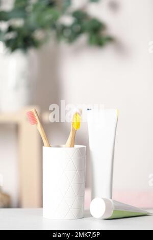 Bamboo toothbrushes and paste on light table indoors Stock Photo