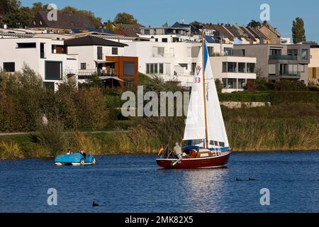 A sailboat and a pedal boat in front of the houses at the Phoenix See in Dortmund, Ruhr area, North Rhine-Westphalia, Germany Stock Photo