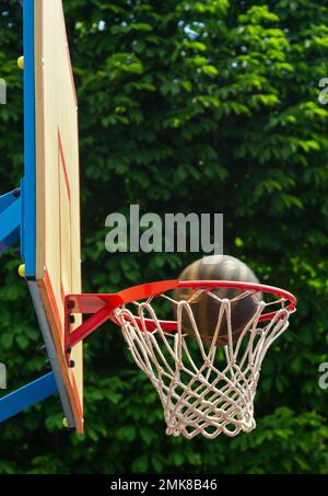 A basketball in the net. The fly ball is in the ring. A sports game. Conceptual: victory, success, hitting the target, sport. Successful ball throw. Stock Photo