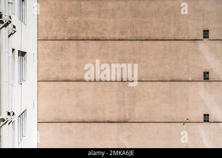 View of a plastered building elevation wall with a pattern of floor lines and windows; a texture of a house facade on a bright day Stock Photo