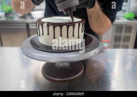 cake pastry chef designer decoration a dark chocolate frosted icing white cake with brown dripping with ganache filling Stock Photo