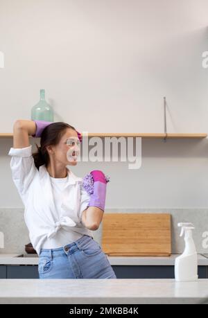 A joyful woman in rubber gloves after home cleaning with a mocap of a pulvilizer with cleaning agent. Cleaning Stock Photo