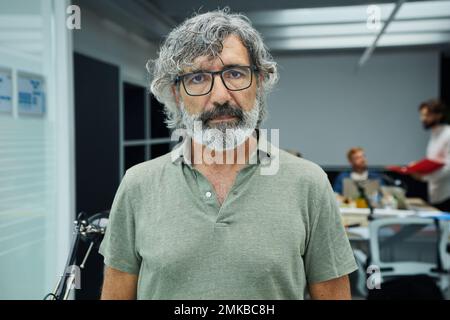 Serious mature business man looking at camera standing in office at team board meeting. Stock Photo