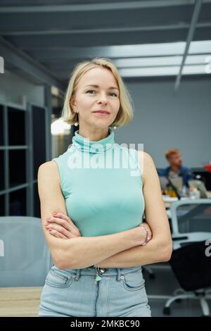 Vertical confident Caucasian business woman looking at camera standing with arms crossed in office.  Stock Photo