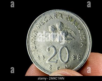 Closeup finger holding old 20 cent Malaysia coin on a black background. Stock Photo