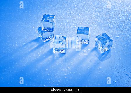 Cold ice cubes on reflective surface with water drops Stock Photo