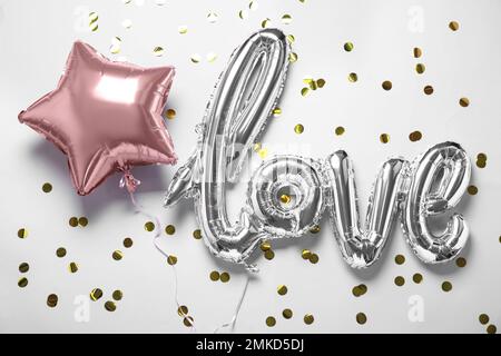 Foil star shaped and LOVE balloons on white background, above view Stock Photo
