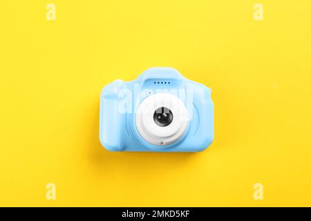 Light blue toy camera on yellow background, top view Stock Photo