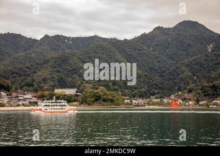 Hiroshima Japan 3rd Dec 2022: the ferry is on the way from Miyajima guchi to Island Itsukushima. Background is the torii of Itsukushima Shrine. Stock Photo