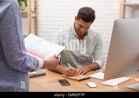 Colleagues making schedule using calendar in office Stock Photo