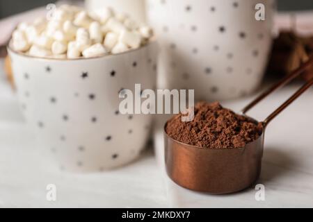 Cocoa powder in scoop and hot drink on white wooden table Stock Photo