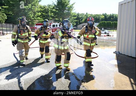 Col. Taona Enriquez, center, installation commander, and Chief Master Sgt. Alan Weary, second from left, installation command chief, carry a fire hose during a firefighting training event at Hanscom Air Force Base, Mass., Sept. 8, while Hanscom fire fighter Joshua Elsten, left, and Fire Lt. Keith Williams, look on. The 66th Civil Engineering Division Fire Department hosted the leaders to demonstrate what firefighters experience during training and real-world events. Stock Photo