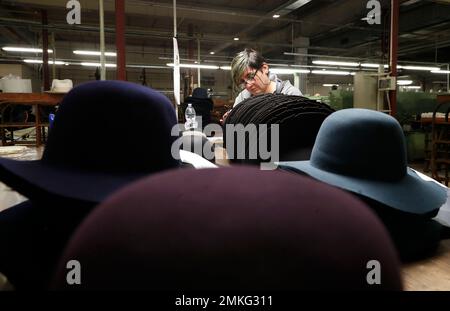 A woman works on hats inside the Borsalino hat factory in