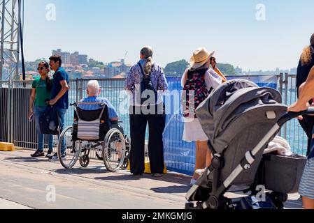 A wheelchair-bound person at Circular Quay watching activities on Sydney Harbour on Australia Day January 26th, 2023 Stock Photo