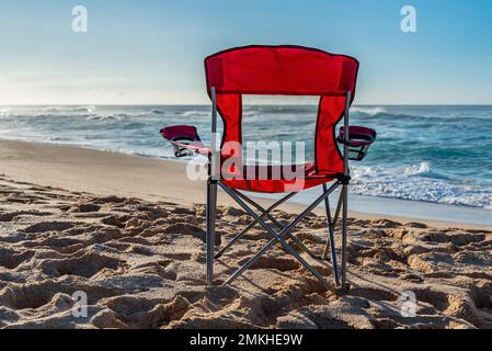 An empty red beach chair facing the water on Sunset Beach, Hawaii Stock Photo