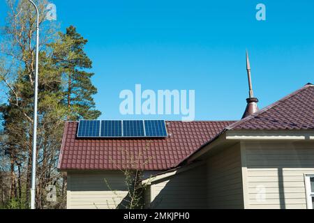 Solar panels on the roof of a private one-story house in the countryside. Eco-friendly use of solar energy, an alternative source. Caring for nature, Stock Photo