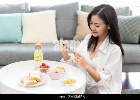 The young lady sitting on the sofa playing mobile phone games Stock Photo