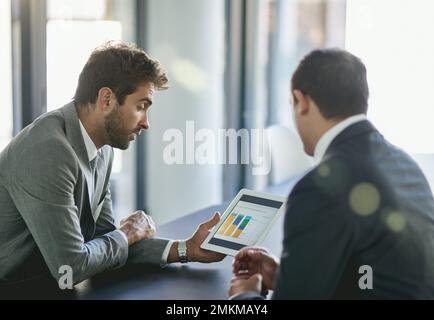 Analyzing profit and loss. two colleagues looking at a graph on a digital tablet together in an office. Stock Photo