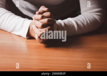 Tanned female hands holding hands in prayer. Copy space. Stock Photo