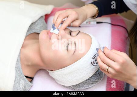 Procedure at a cosmetologist, cleansing the face of cosmetics and preparing the face for massage, close-up procedure. Stock Photo