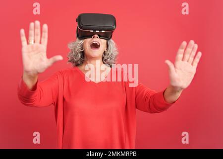Surprised mature woman using virtual reality goggles Stock Photo