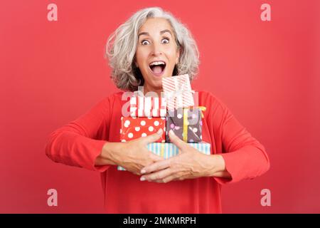An excited mature woman receiving many gifts Stock Photo