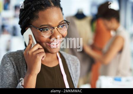 Getting good feedback on my first collection. a fashion designer talking on her phone. Stock Photo