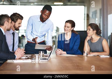 Everyones input is important. a group of corporate colleagues talking together over a digital tablet in an office. Stock Photo