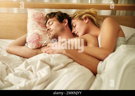 So close, they even share the same dreams. a young couple asleep in bed at home. Stock Photo